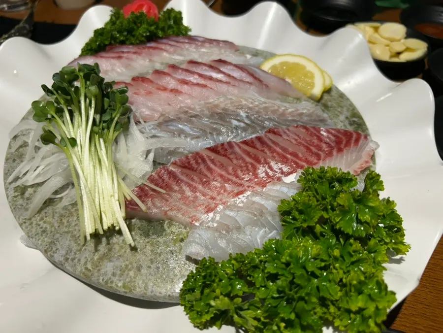 Cerveza sin alcohol servida en un vaso térmico junto a la mesa de sashimi
