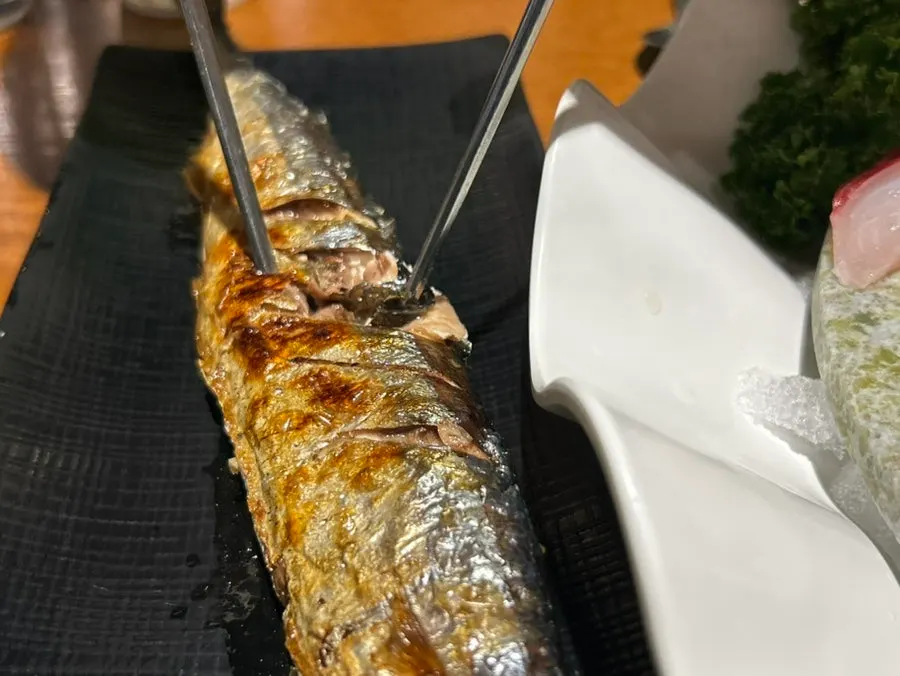 Un trozo de sashimi de mújol gris levantado con los palillos