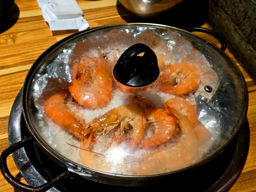 Salt-grilled king shrimp cooking on the salt bed