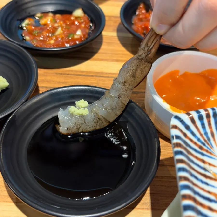 Raw shrimp sashimi dipped in wasabi-soy sauce