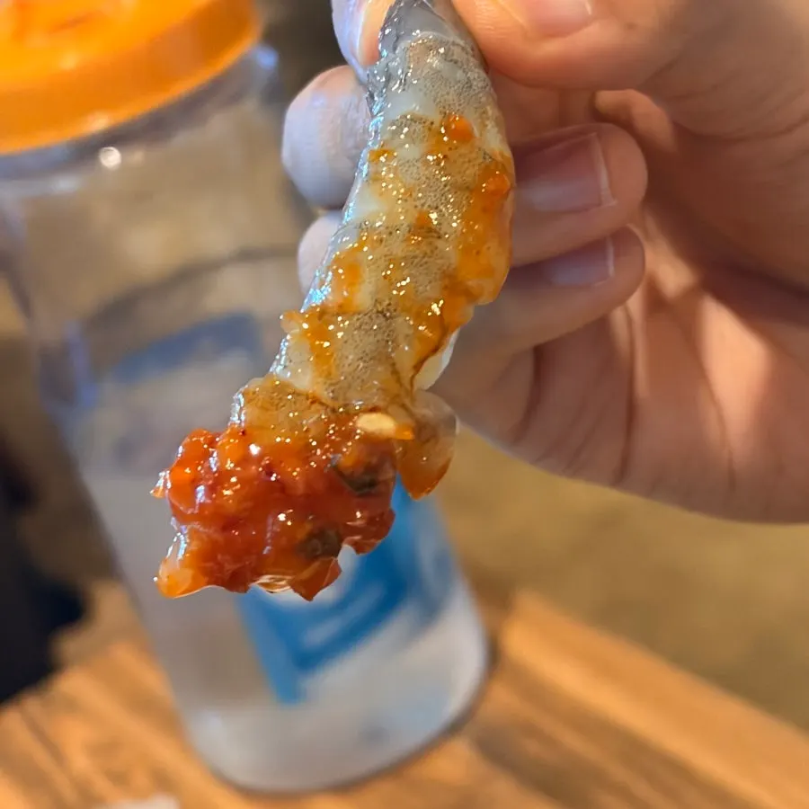 A piece of raw shrimp sashimi dipped in makjang