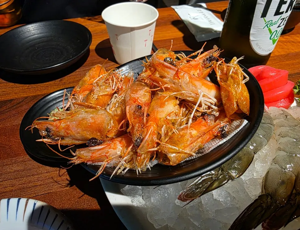 Cabeza de gamba asada servida junto al sashimi de gamba viva