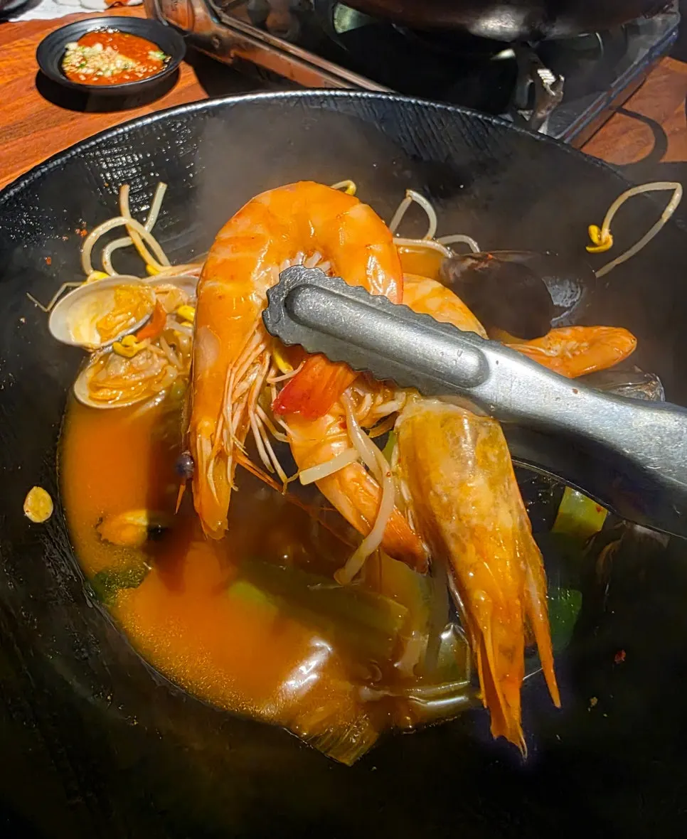 Fideos del ramyeon de mariscos levantados con los palillos