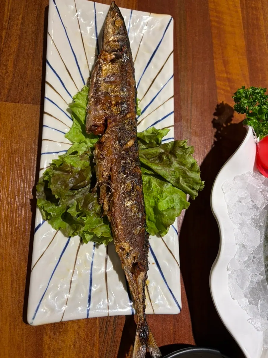 A bite of sushi with seaweed, pollock roe, wasabi and sashimi