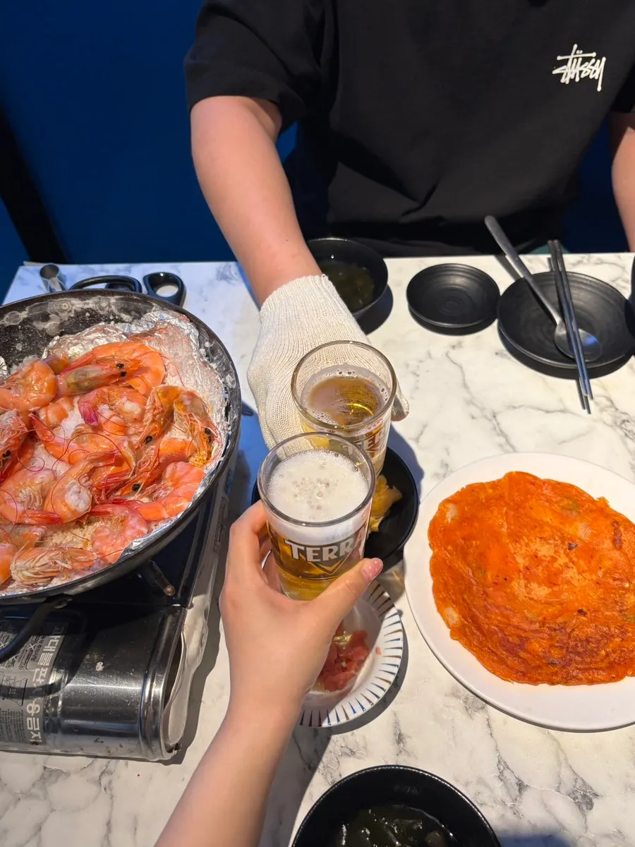 Clinking drink glasses next to grilled shrimp spread