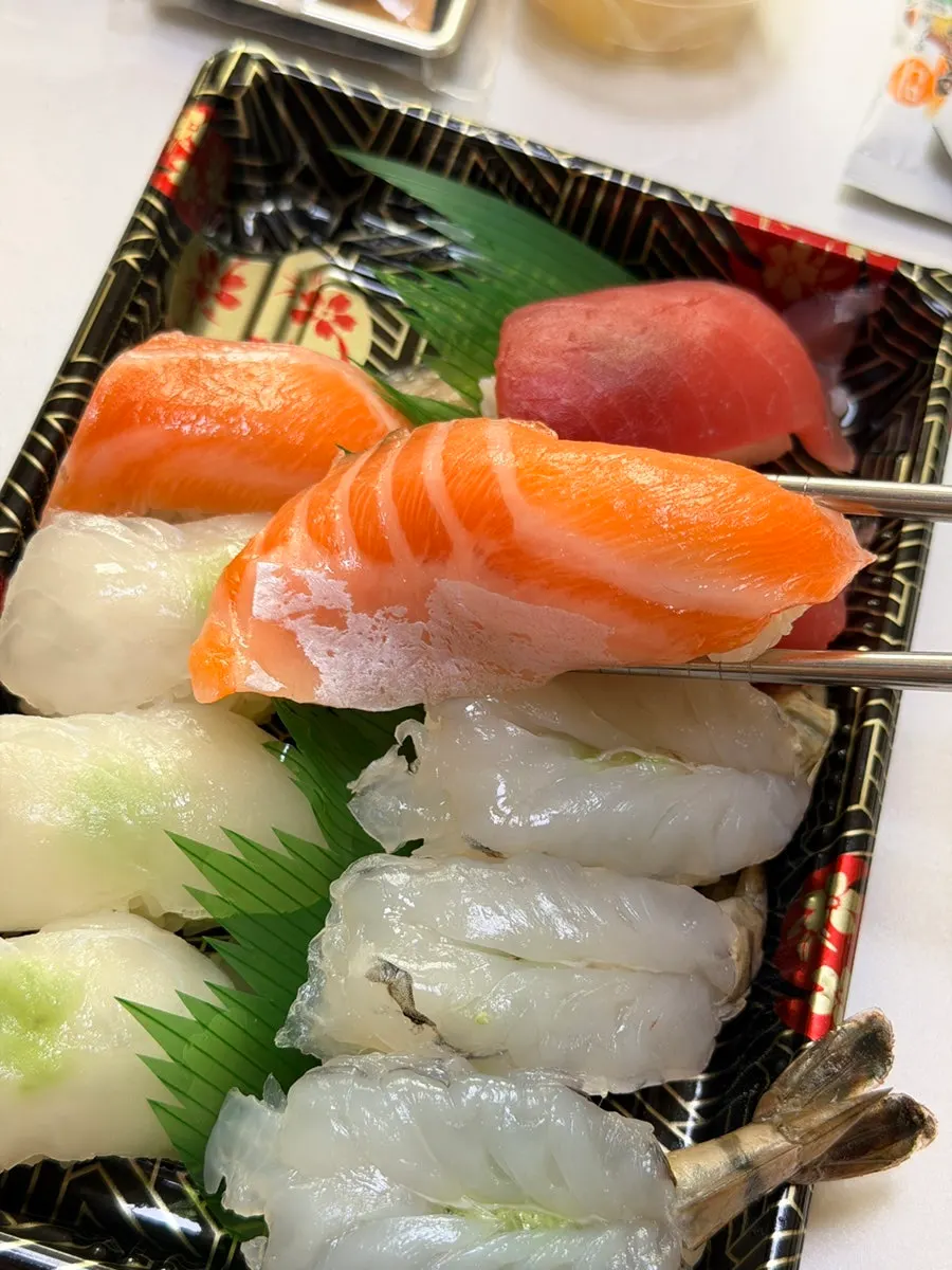 Salmon sushi with fish stretching as it's lifted