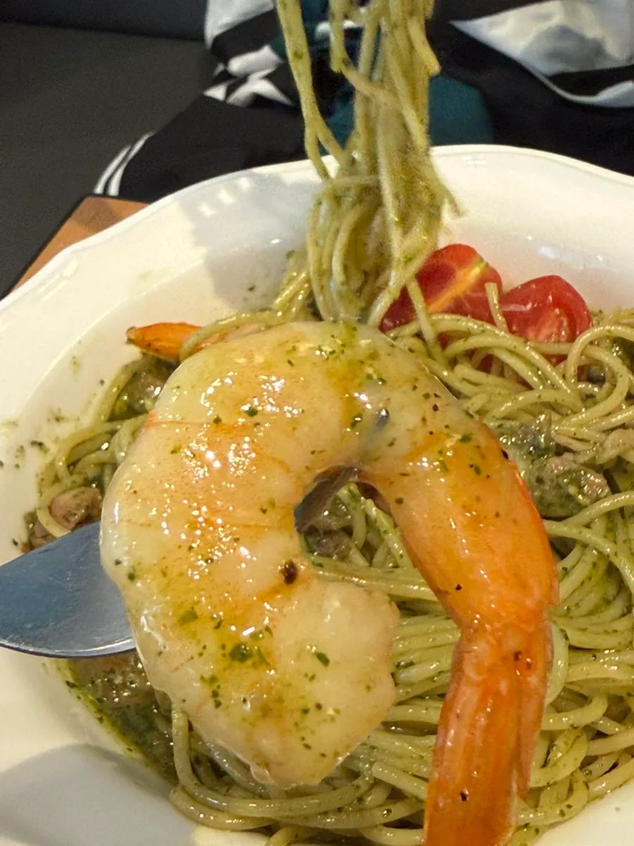 Close-up of bacon and shrimp mixed into the basil pasta