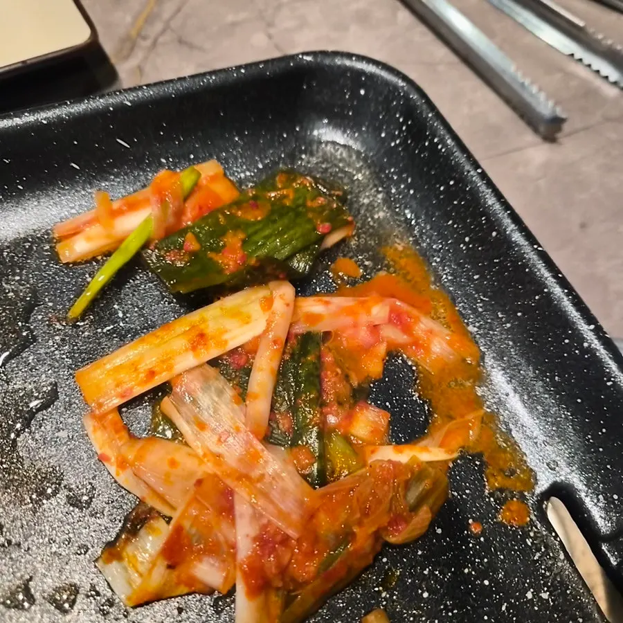 불판에 올린 파김치와 오리고기