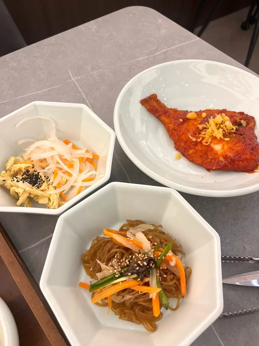 Two flounder pieces, chicken breast egg salad and japchae side dishes