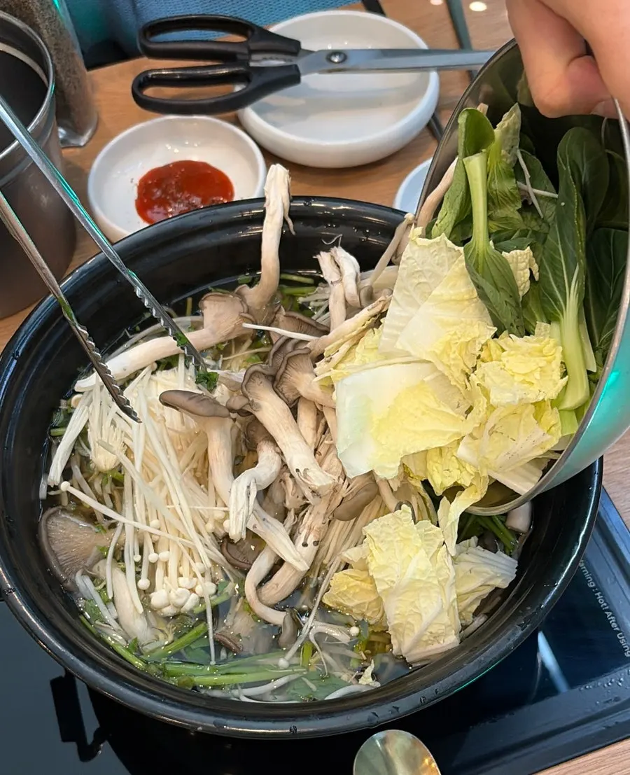 Adding minari and vegetables to the boiling broth