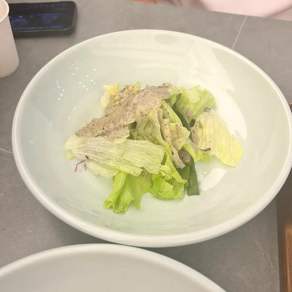 Black sesame dressing salad served in a porcelain bowl