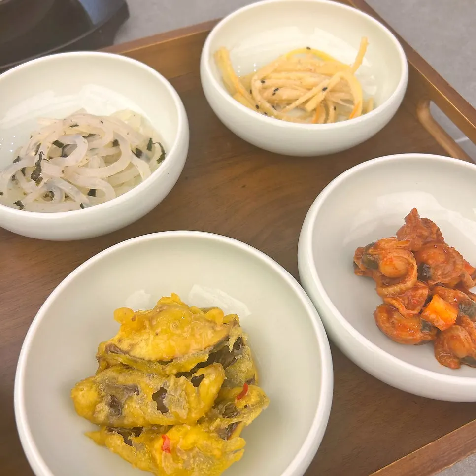 Bowls of napa cabbage kimchi and scallop sauce banchan