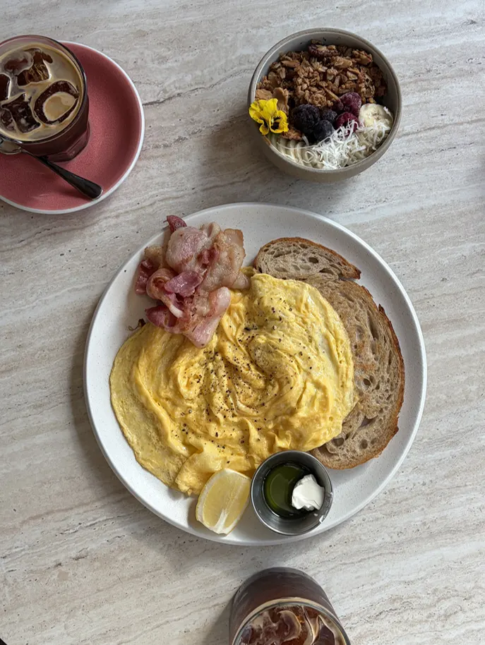 Plated scrambled eggs, bacon, and rye bread