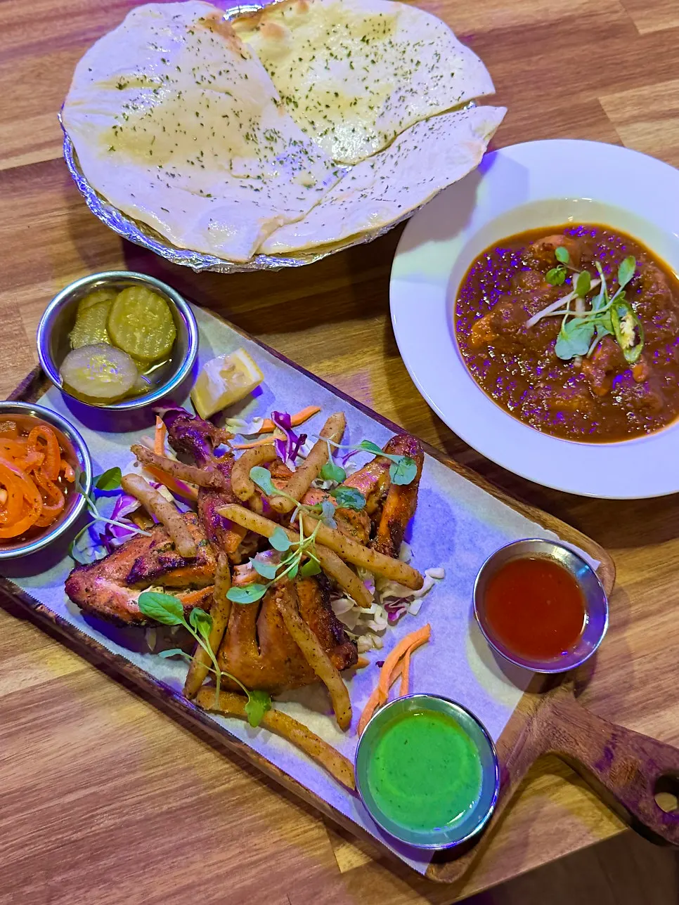 Table setting with tandoori chicken, curry and naan