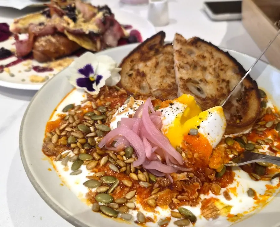 Garlic butter egg topped with yogurt, poached egg, and onion chips