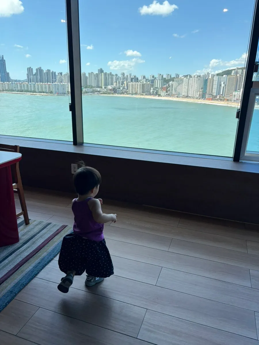 A child looking out at the sea through the window