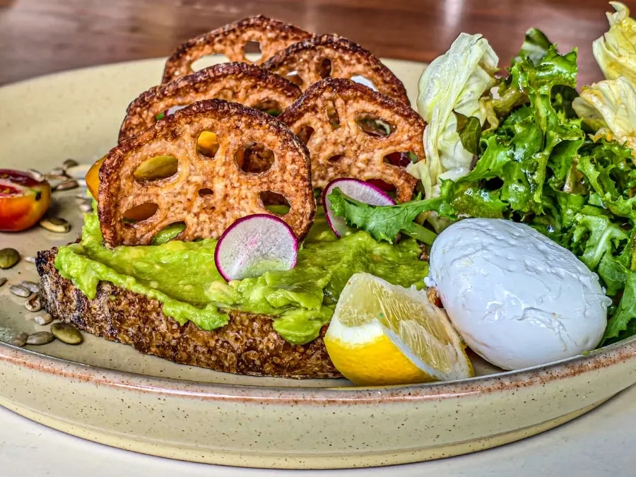 Avocado toast topped with lotus root chips, cheese, and salad