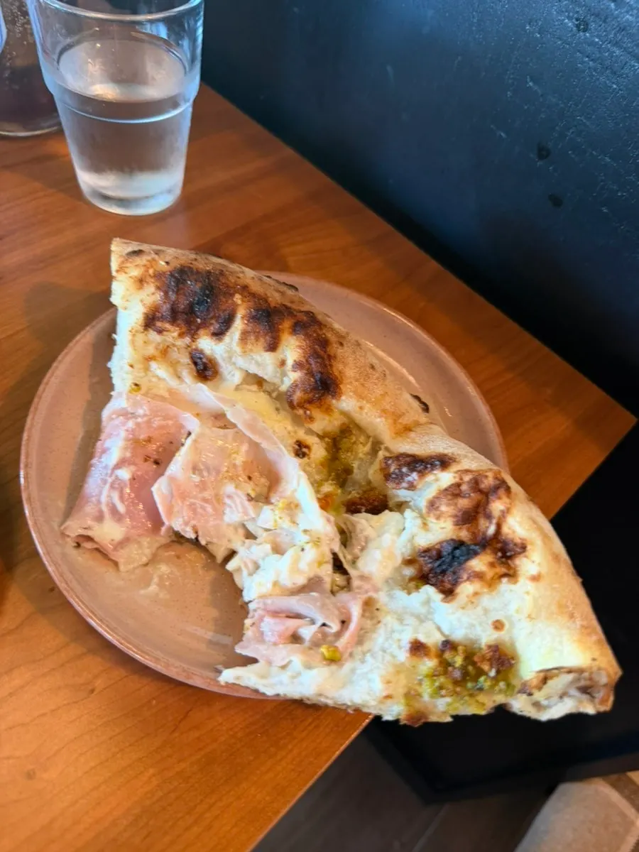 A table shot of jambon pizza with the sea in the background