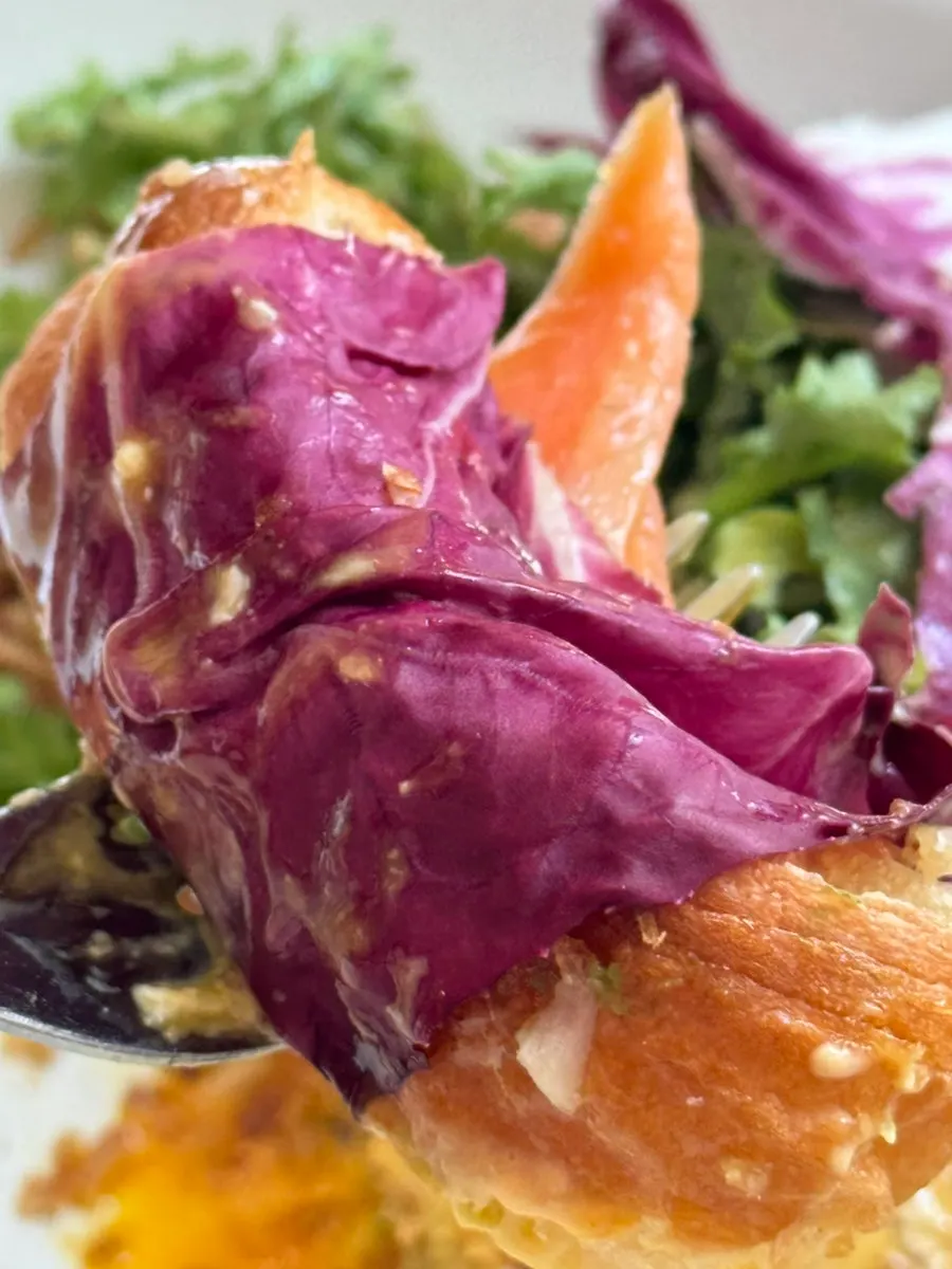 A bite combining salmon, croissant, and poached egg