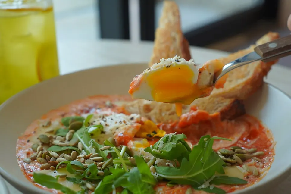 Dipping bread into the shakshuka sauce