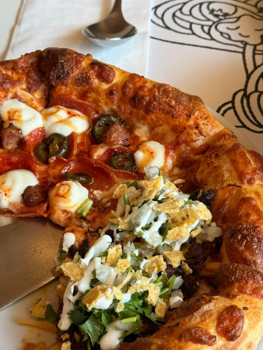 Birria taco pizza topped with meat and cilantro