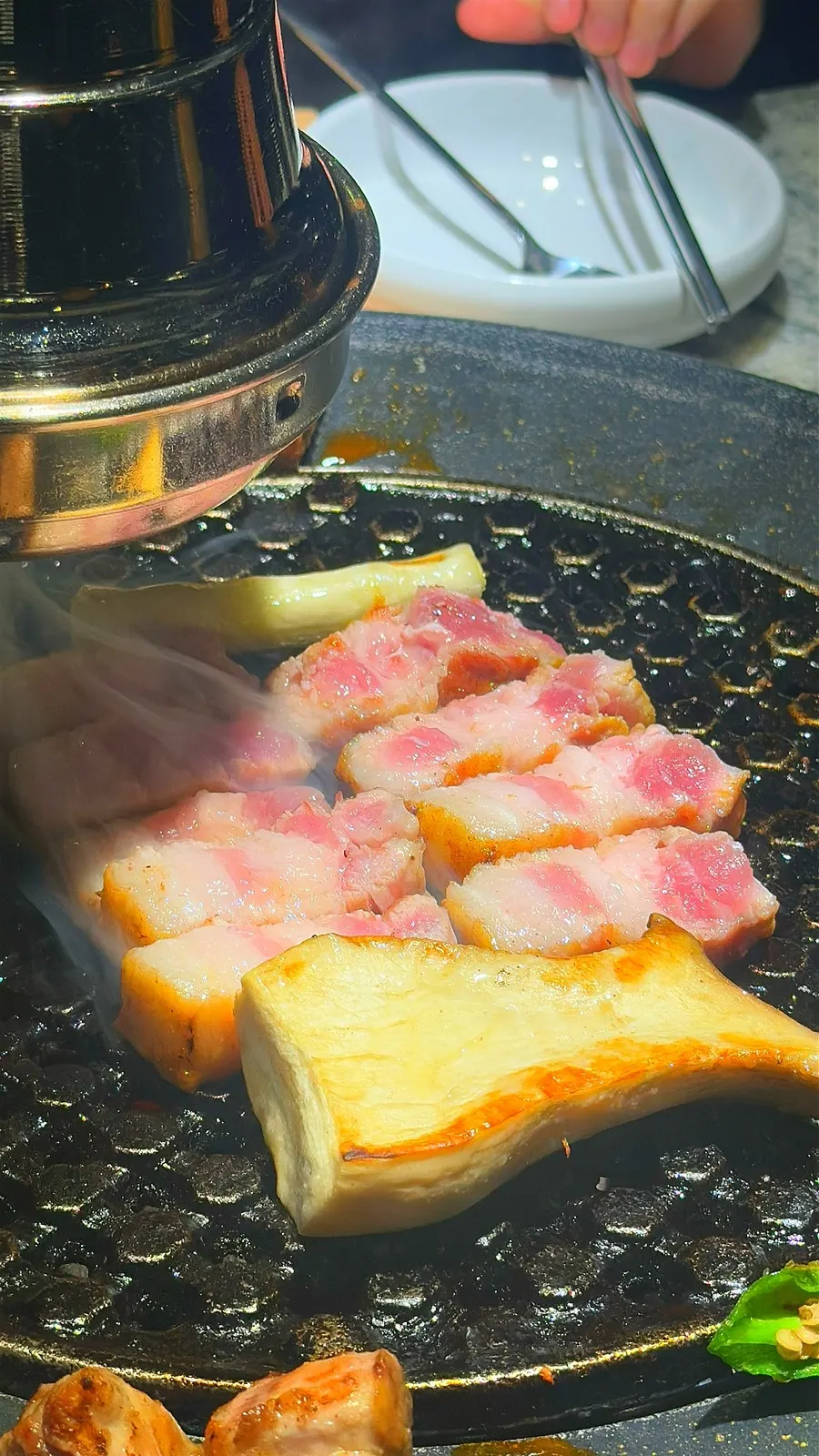 A staff member grilling charcoal pork belly