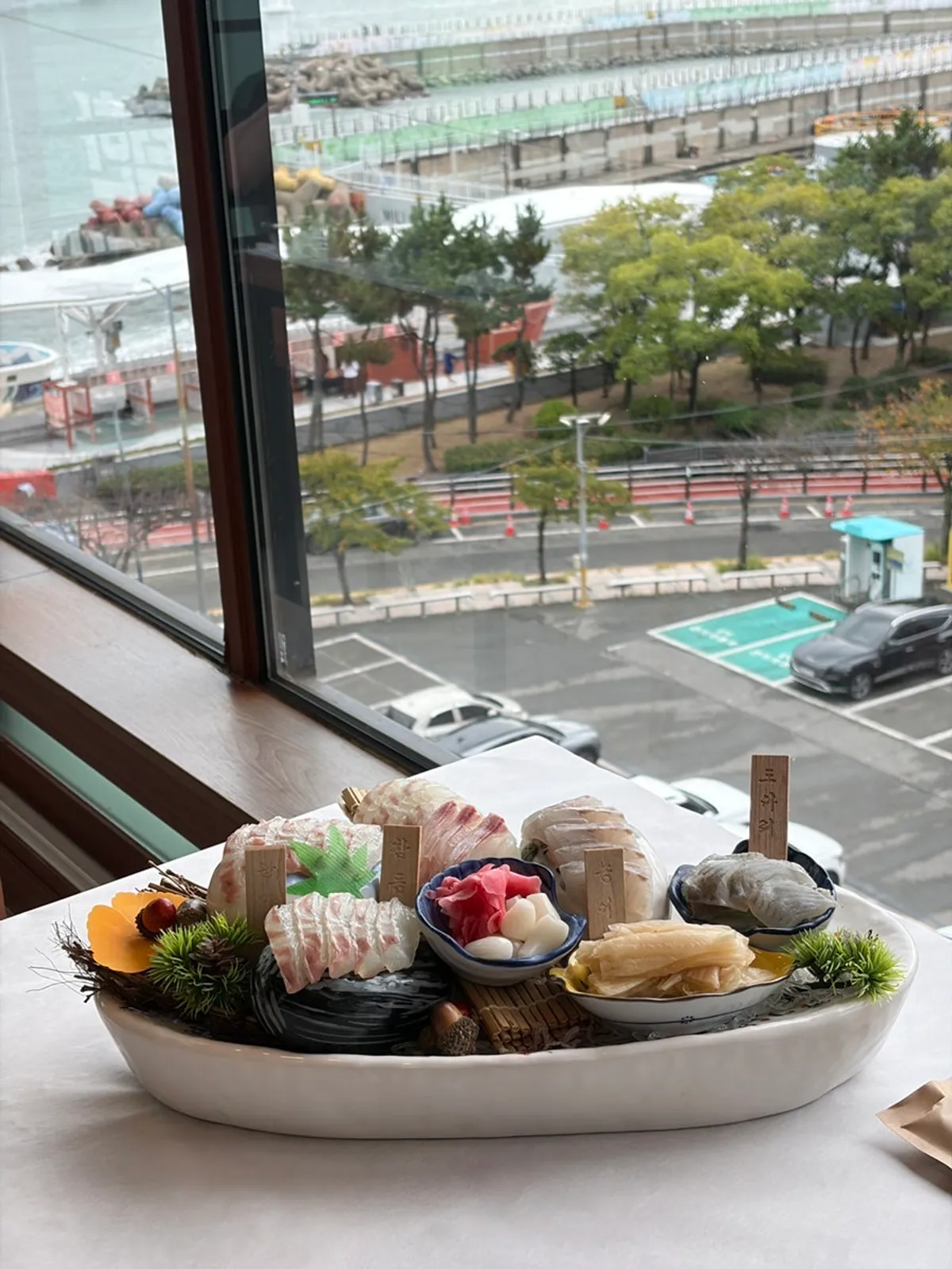 Gwanganda Jjji sashimi spread set by the window overlooking the sea