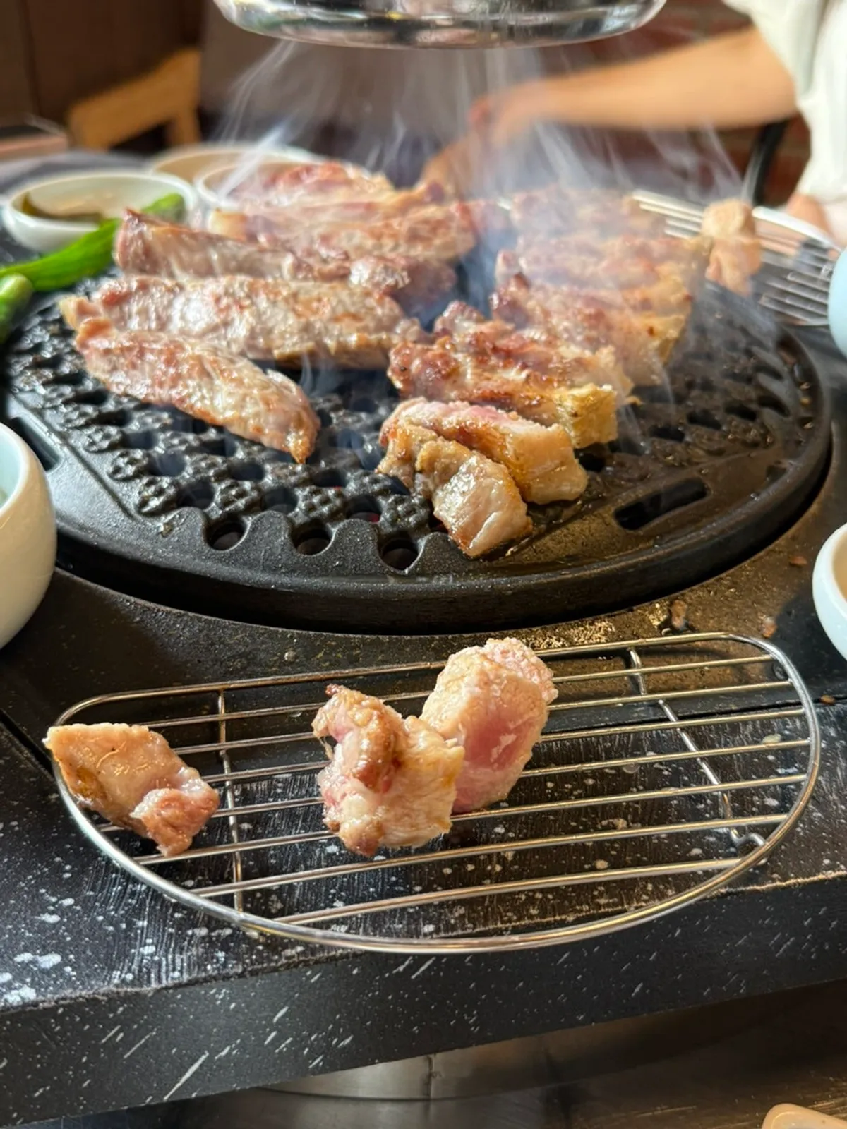직원이 불판에서 두툼한 고기를 굽는 모습