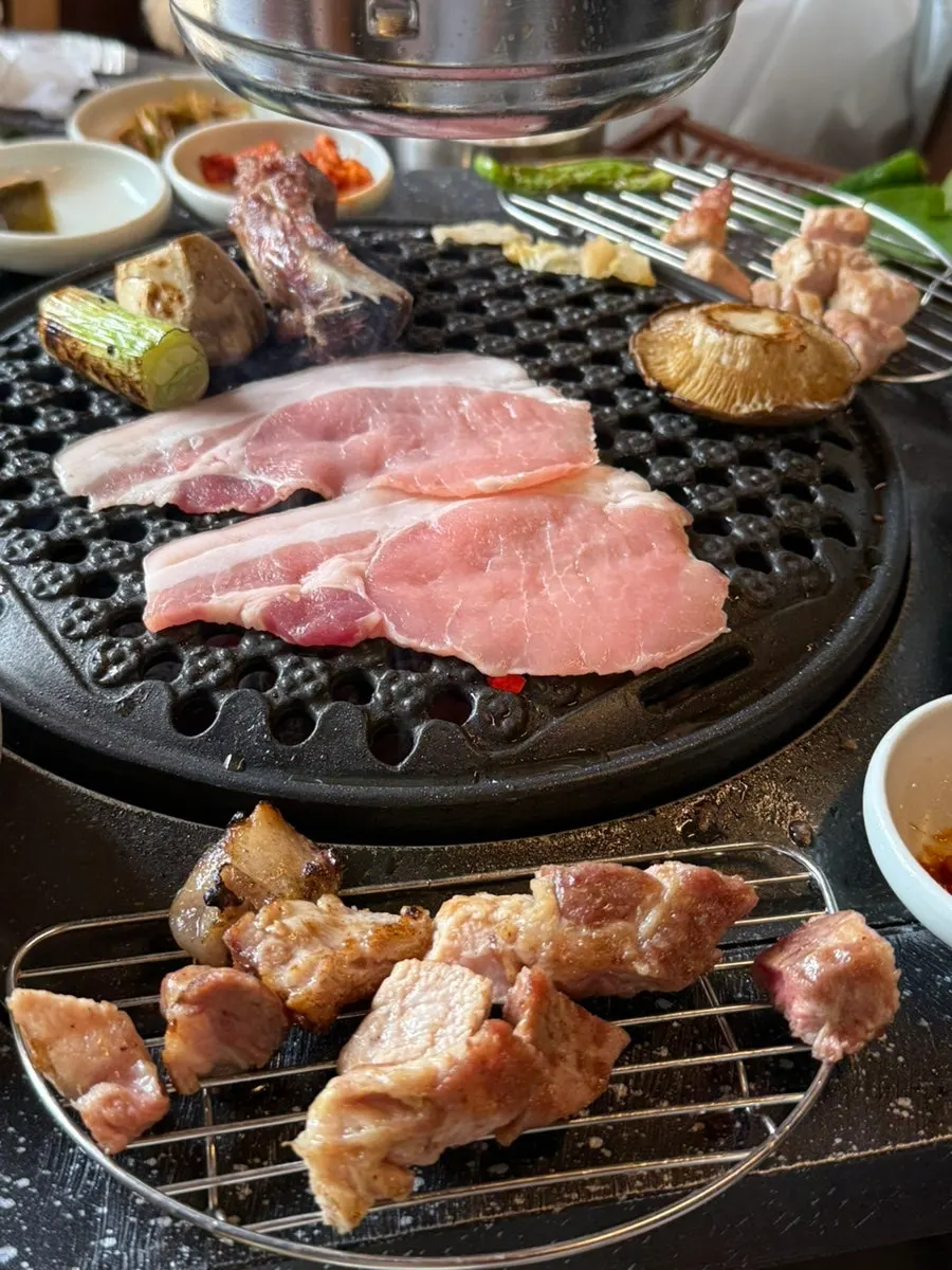불판 위에 쌓인 고기 산더미와 구운 야채