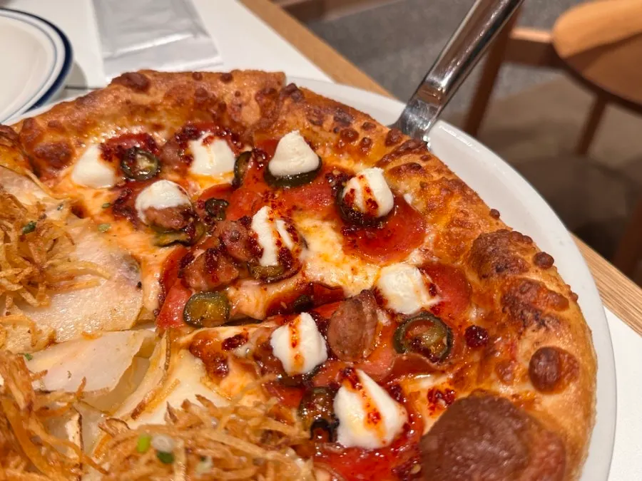 A slice of potato pizza showing the dough and potato toppings