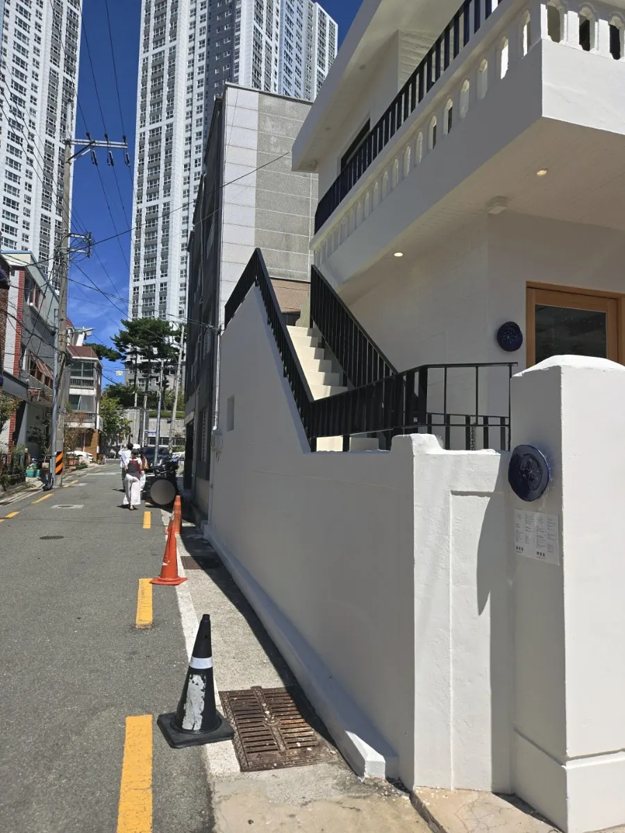 Entrance of Extra Mile, a white house exterior tucked in an alley