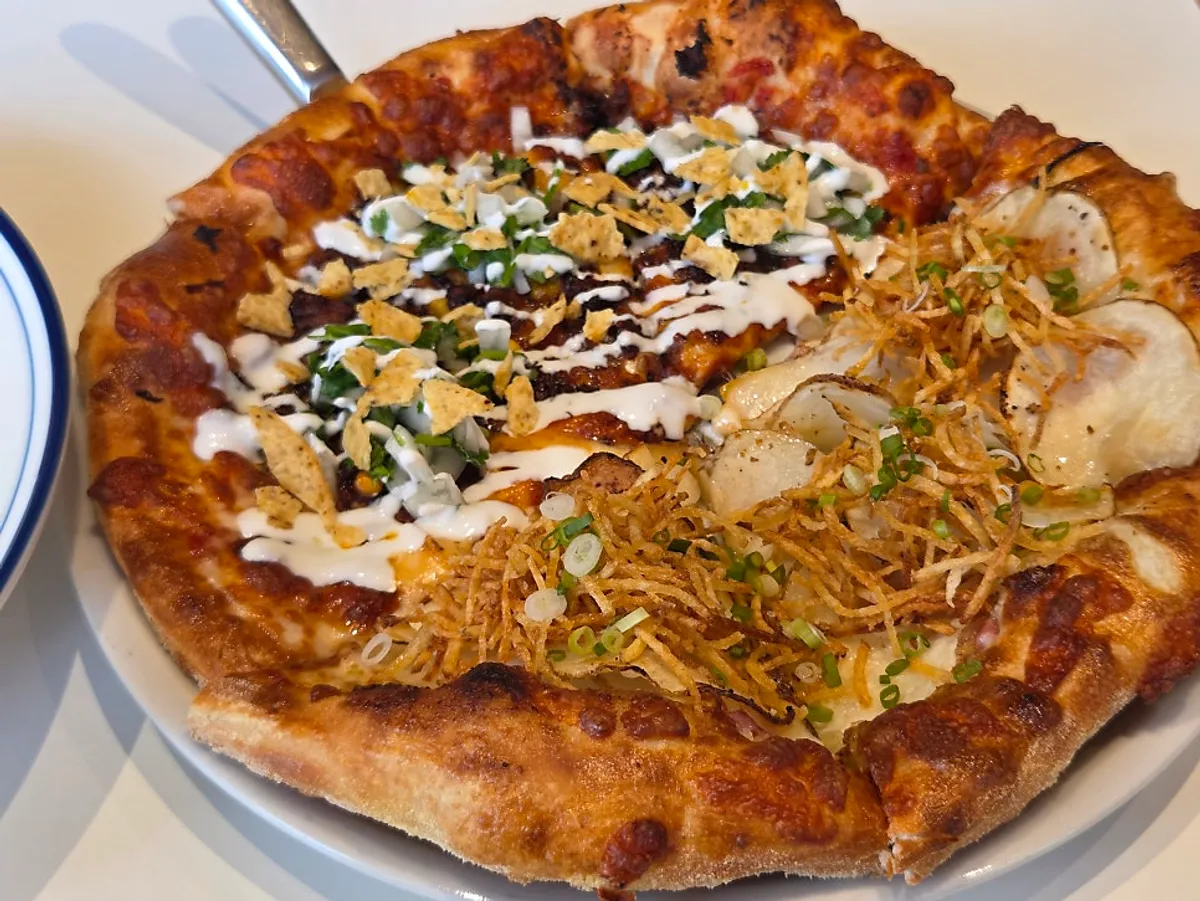 A slice of taco pizza with meat, vegetables, and nacho chips