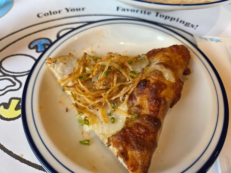 A slice of potato pizza showing the potato toppings