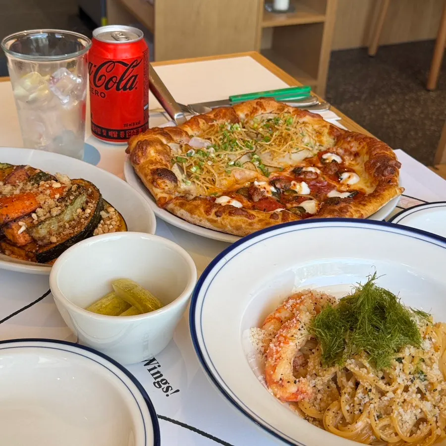 Table spread of pizza, pasta, and grilled vegetables