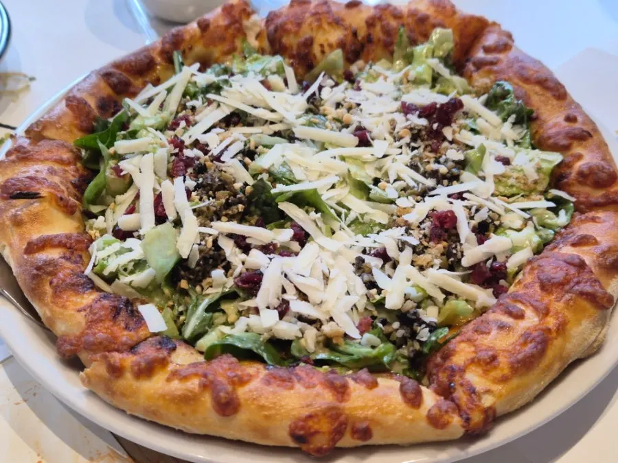 Salad pizza topped with European greens and cranberries