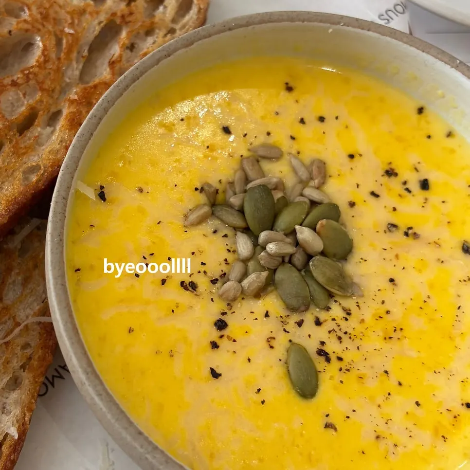 A bowl of pumpkin soup topped with mustard greens