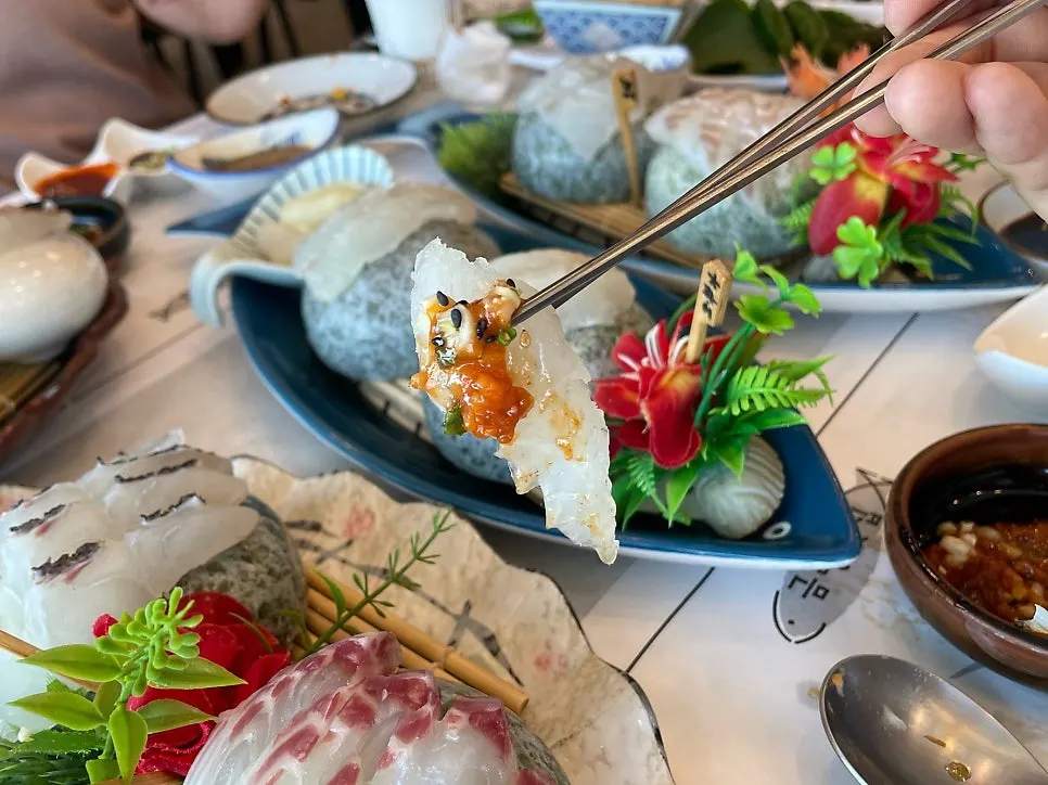 A piece of sashimi served with ssamjang, soy sauce, and wasabi