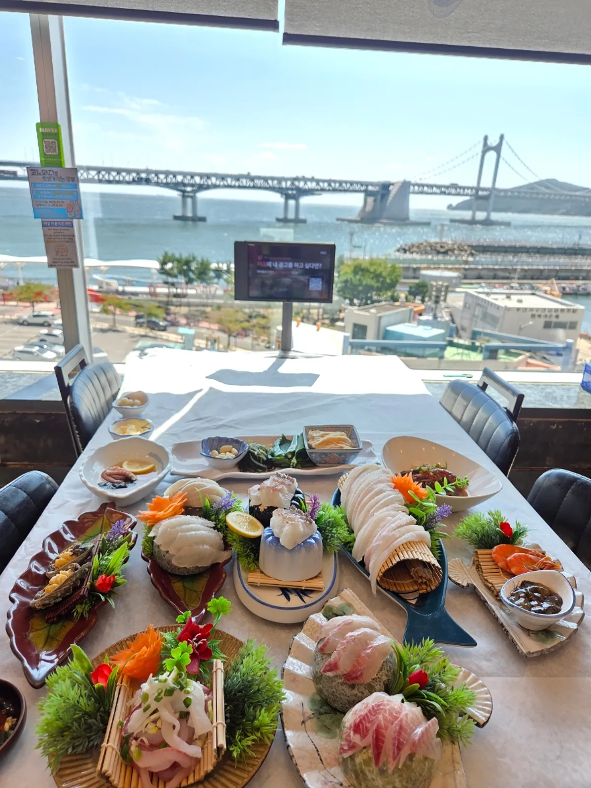Premium mixed sashimi plate set against a Gwangan Bridge backdrop