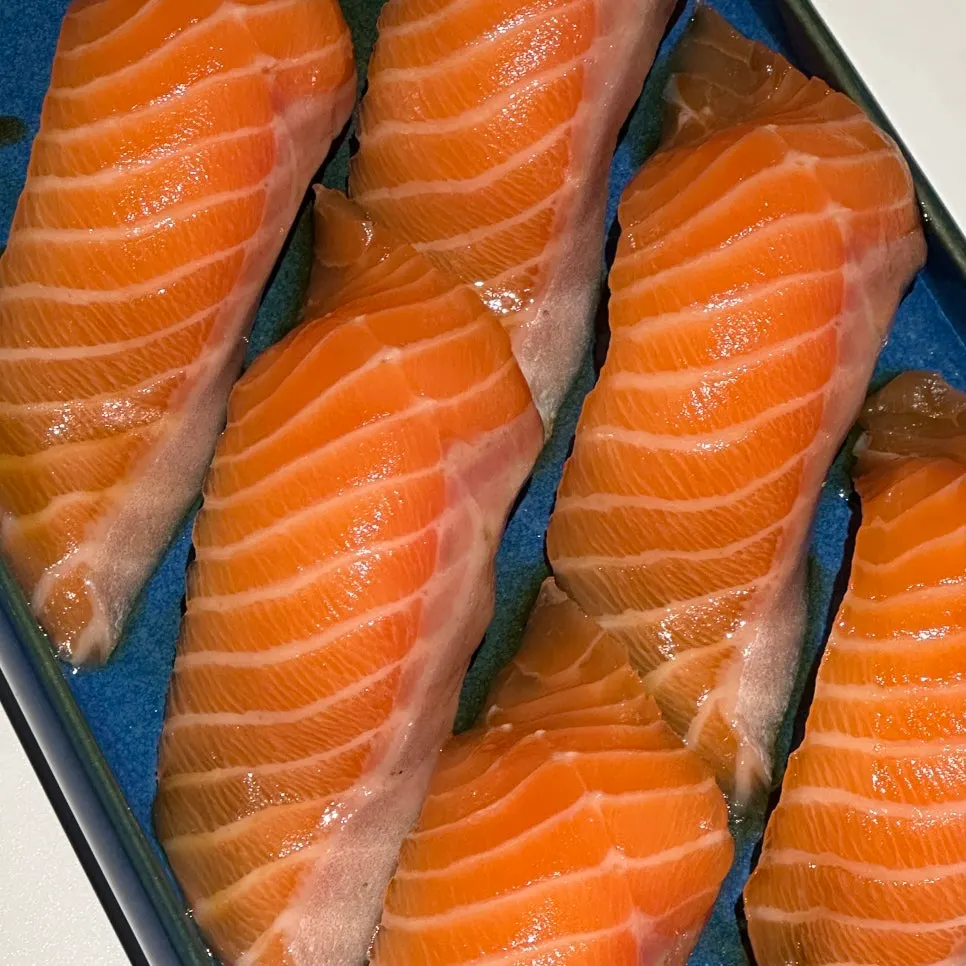 Giant salmon sushi topped with a large, long slice of salmon