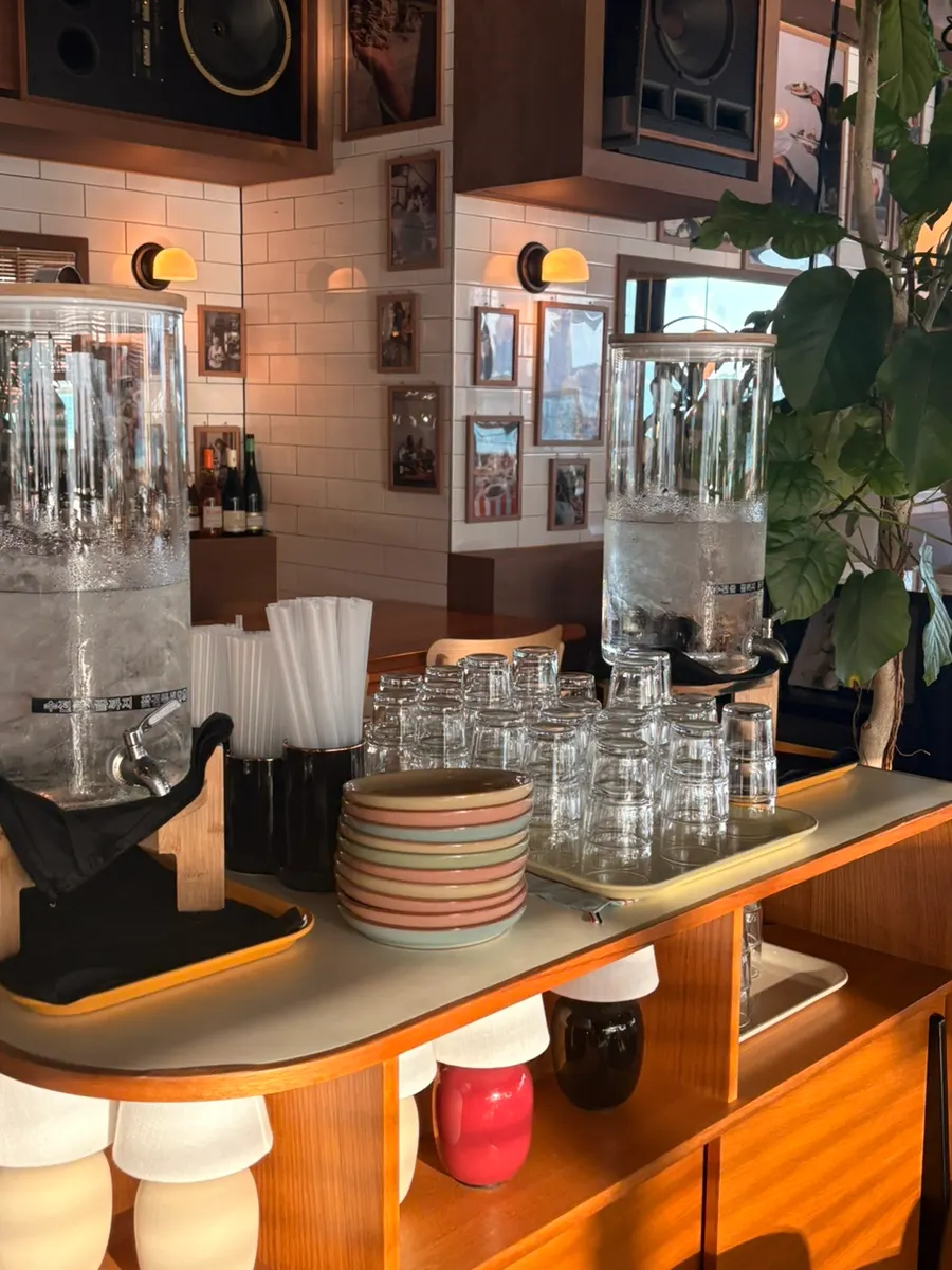 Self-service bar with cups, water, and plates
