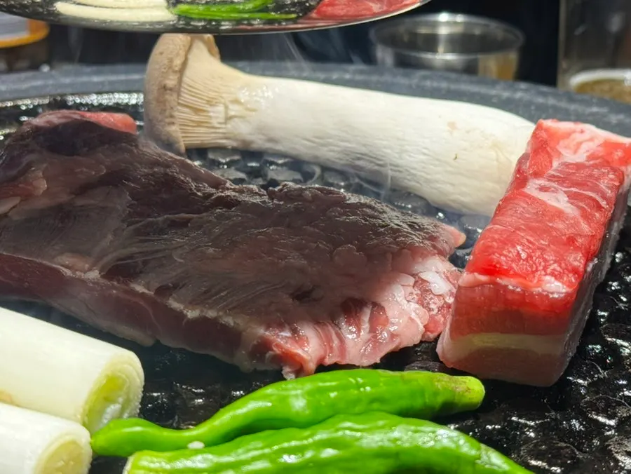 Meat placed on the charcoal grill by staff