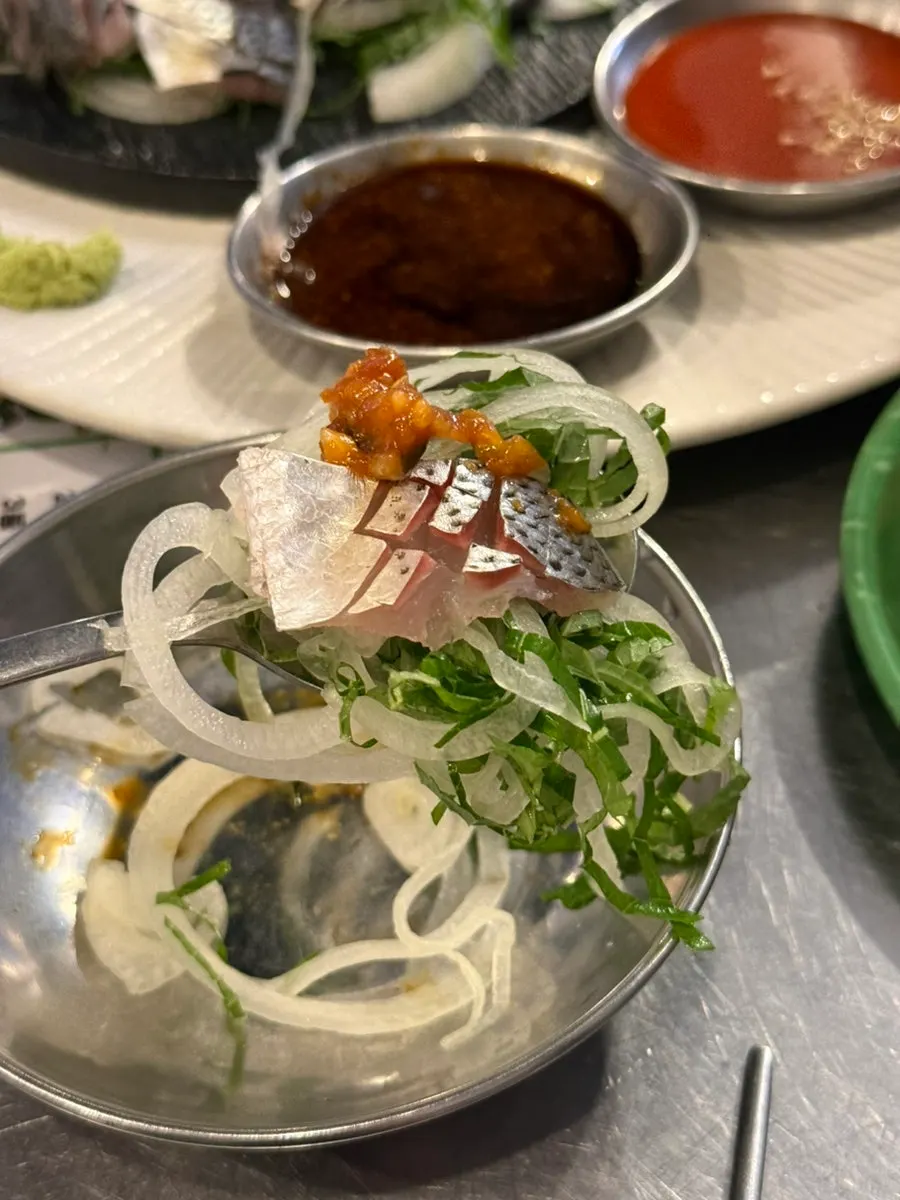 沾醬享用的鰶魚生魚片