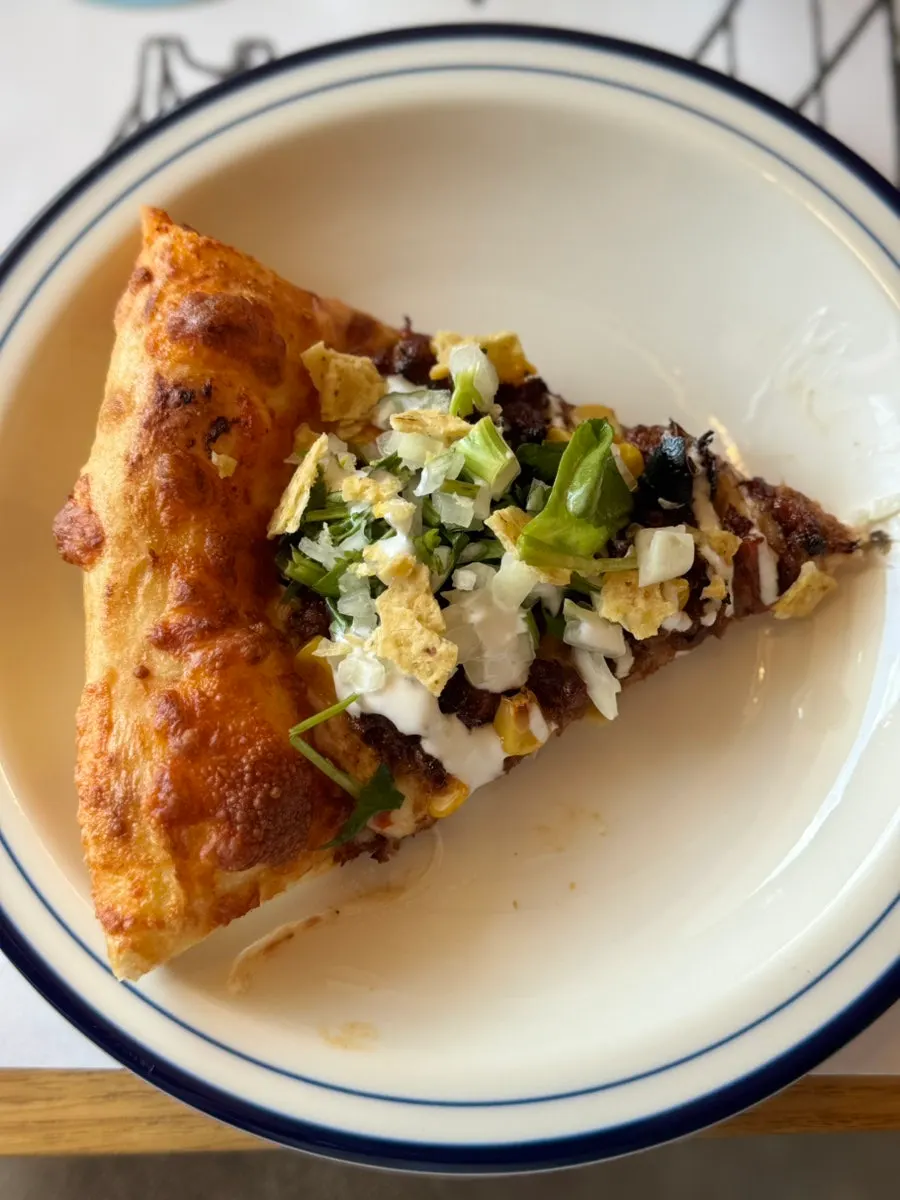 Taco pizza topped with salsa and sour cream