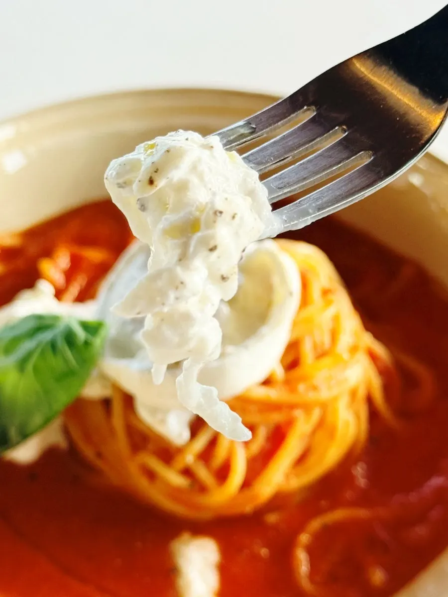 Red ragù pasta topped with cheese and basil