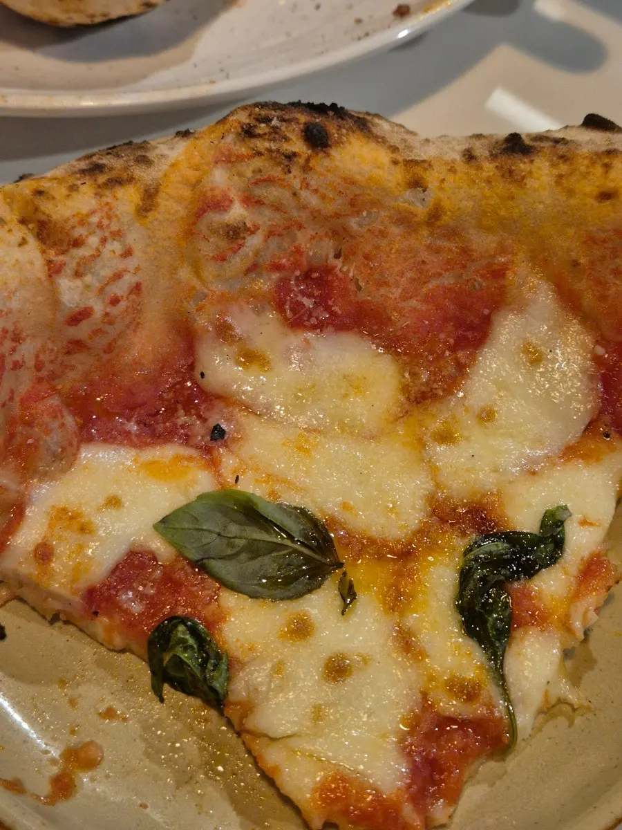 A slice of Margherita pizza with melted cheese