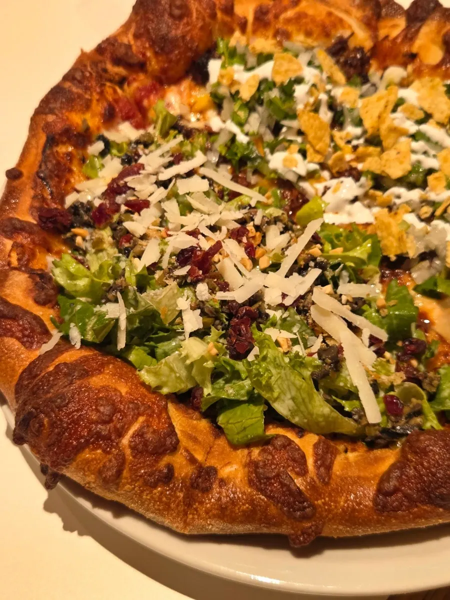 Sliced salad pizza and birria taco pizza