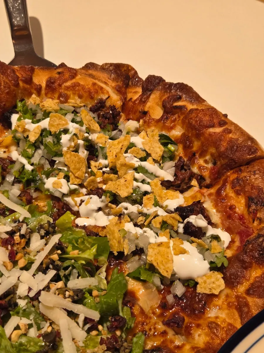 A slice of salad pizza topped with dressing