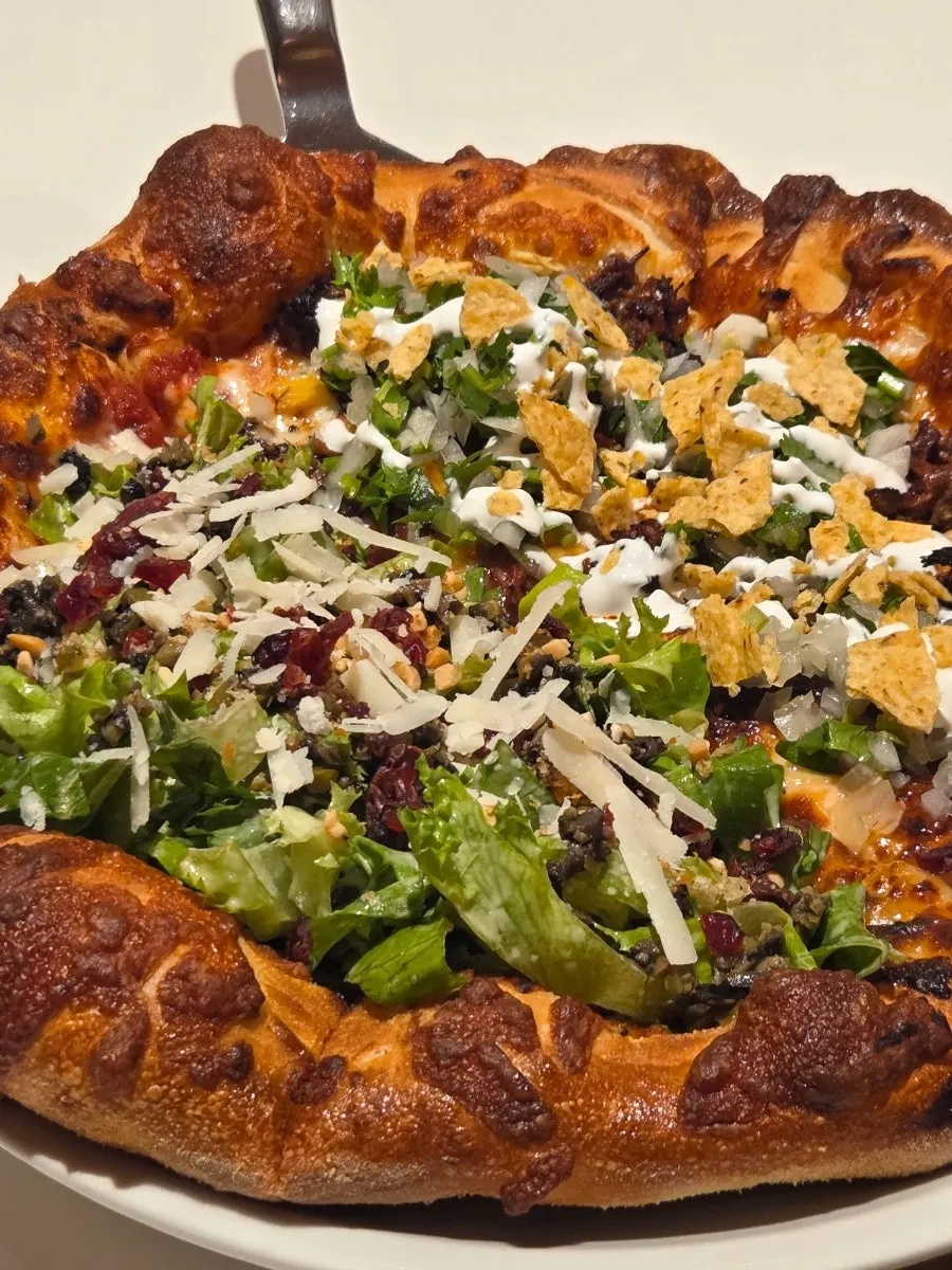 Birria taco pizza topped with nacho chips and sour cream