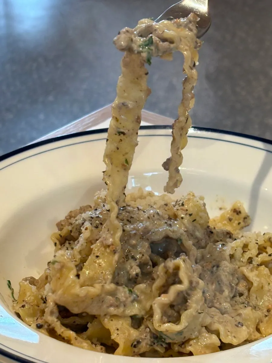 White ragu pasta topped with Reggiano cheese and parsley