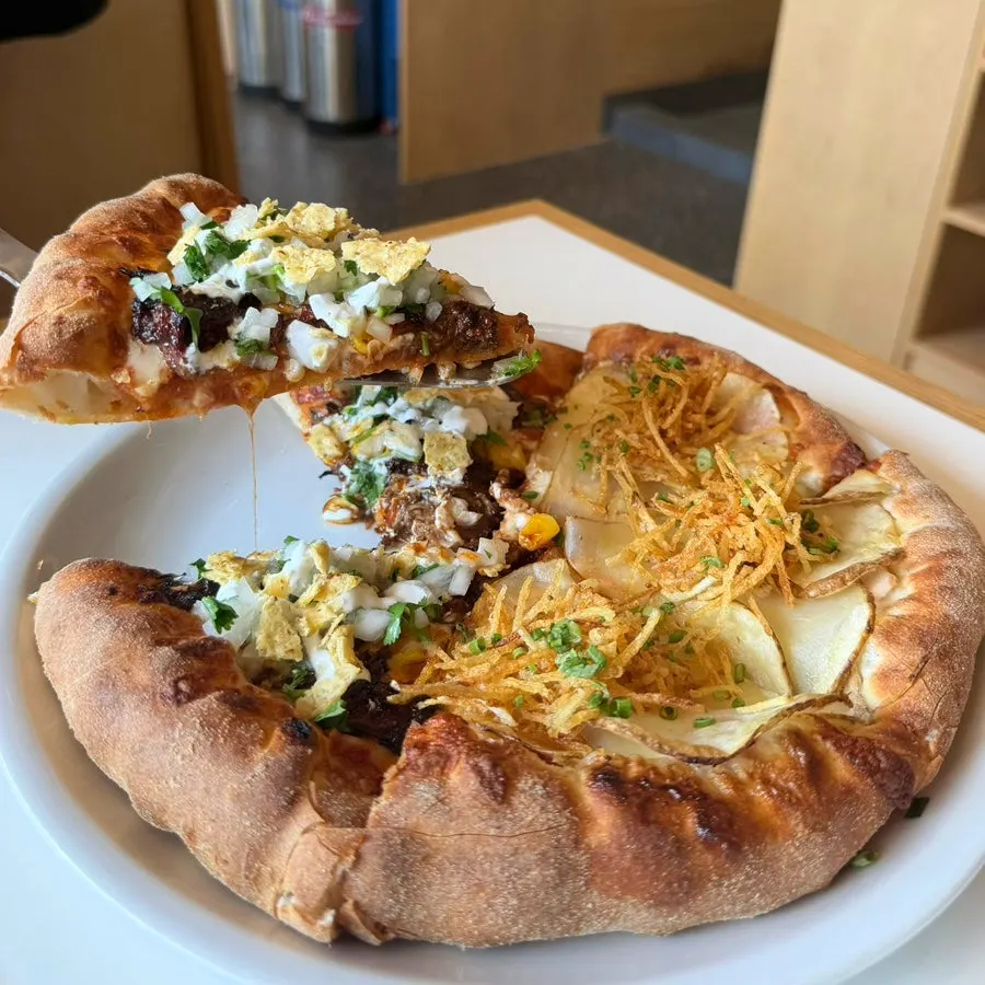 A slice of birria taco pizza topped with cilantro salsa